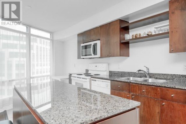 Kitchen with dark wood cabinets, granite countertops, and white appliances. - 1510 - 361 Front Street W, Toronto