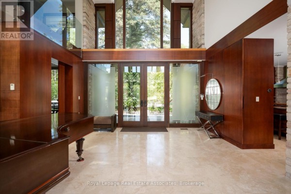 Spacious foyer with marble floors, rich wood paneling, double glass doors, and a piano. - 1510 Pinetree Crescent, Mississauga