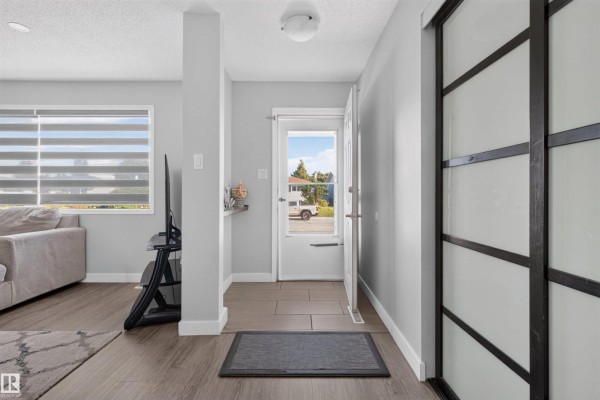 Interior entryway with tile flooring, a white door to the outside, and large sliding closet doors. - 15104 74 St Nw, Edmonton