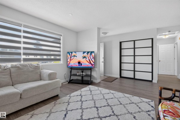 Living room with a television on a stand, a sofa, and a sliding door closet. - 15104 74 St Nw, Edmonton