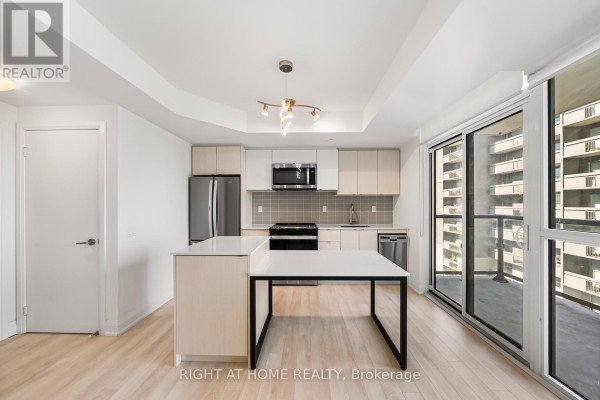 Kitchen area with light wood cabinets, stainless steel appliances, and white island. - 1511 - 1461 Lawrence Avenue W, Toronto