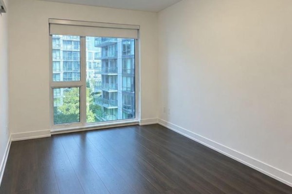 Room with dark hardwood floors and a large window showing a city view. - 1511 - 25 Ordnance Street, Toronto