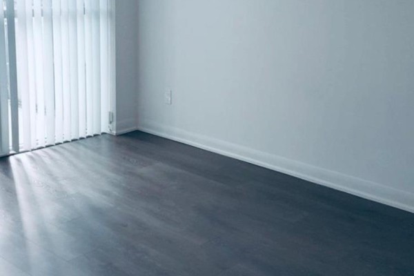 Empty room with dark wood floors and vertical blinds casting light. - 1511 - 5162 Yonge Street, Toronto