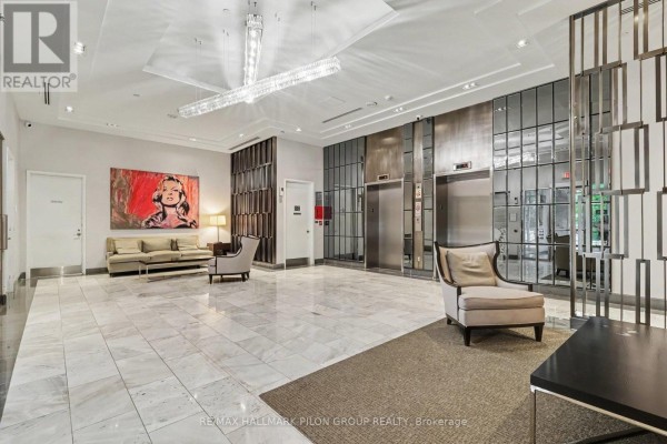 Luxurious apartment building lobby with marble floors, elevators, seating, and artwork. - 1512 - 300 Lisgar Street, Ottawa