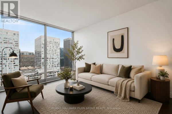 Living room with a large window overlooking city buildings, a sofa, and a coffee table. - 1512 - 300 Lisgar Street, Ottawa