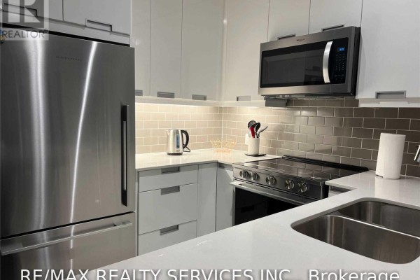 Compact kitchen with stainless steel appliances, white cabinets, and grey tiled backsplash. - 1512 - 35 Watergarden Drive, Mississauga