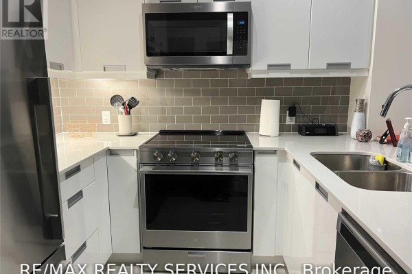 Kitchen area with stainless steel stove, microwave, white cabinets, and quartz countertops. - 1512 - 35 Watergarden Drive, Mississauga