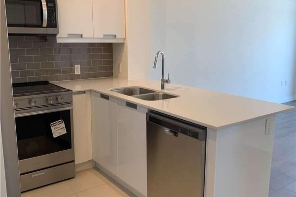 Kitchenette with double sink, stainless steel dishwasher, and white cabinets, connected to the living area. - 1512 - 35 Watergarden Drive, Mississauga