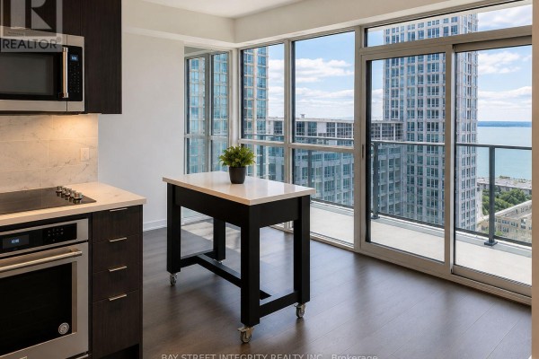 Kitchen with dark wood cabinets, stainless steel appliances, and balcony access with lake view. - 1512 - 38 Iannuzzi Street, Toronto