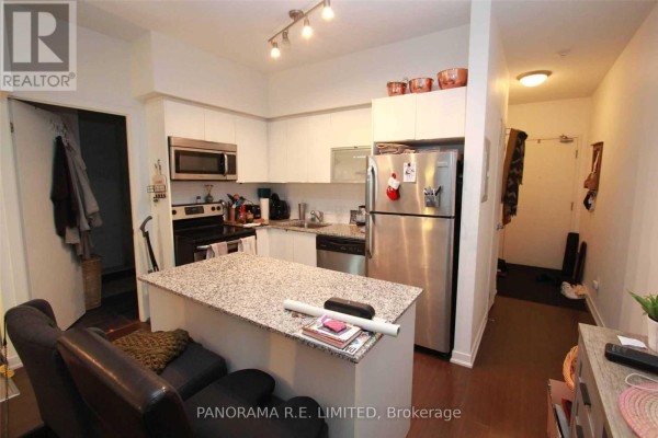 Kitchen with white cabinets, granite island, stainless steel appliances, and dining area. - 1512 - 55 East Liberty Street, Toronto
