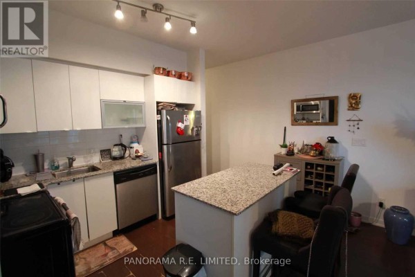 Kitchen with white cabinets, granite island, stainless steel refrigerator, and wine rack. - 1512 - 55 East Liberty Street, Toronto