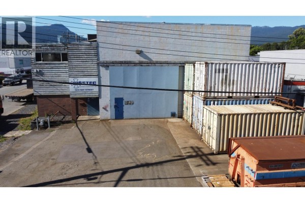 Close-up of building entrance with loading dock, shipping containers and trucks. - 1514 Bay Street, North Vancouver