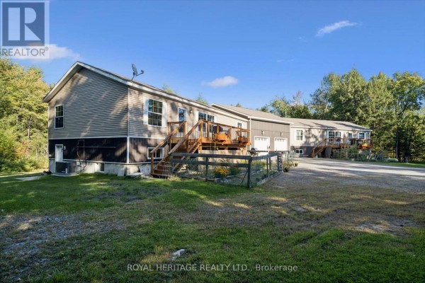 Side view of a multi-family home with grey siding, brown trim, a wooden deck, and a gravel driveway. - 1515 Uffington Road, Bracebridge