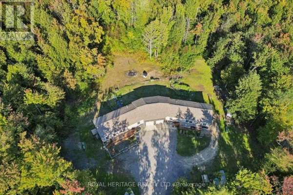 Aerial view of a long, multi-unit building with garages and decks nestled in a dense forest. - 1515 Uffington Road, Bracebridge
