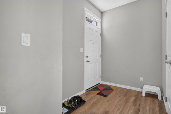 Entranceway of a duplex with a white door, light grey walls, and laminate flooring. - 15150 26 St Nw Nw, Edmonton