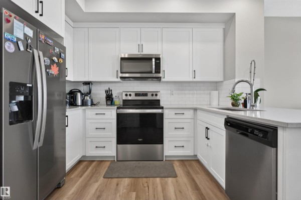 Close-up view of a modern kitchen with white shaker cabinets and quartz countertops. - 15150 26 St Nw Nw, Edmonton