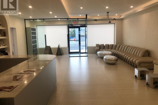 Commercial interior waiting area with a curved sofa, two round silver tables, and a reception desk. - 1517-1519 O Connor Drive, Toronto