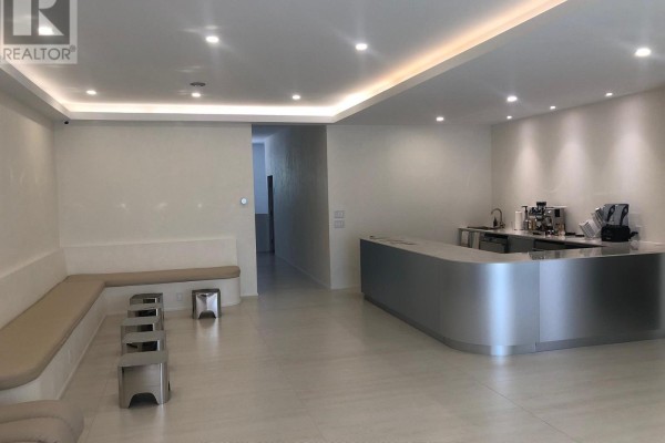Commercial space with a curved silver reception desk, seating area, and hallway leading to a back room. - 1517-1519 O Connor Drive, Toronto