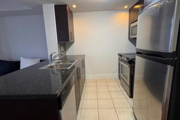 Kitchen with dark wood cabinets, granite countertop, stainless steel appliances and tiled floor. - 1519 - 500 Doris Avenue, Toronto
