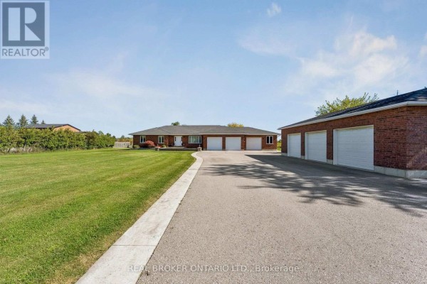 View of the detached garage with six doors from the driveway, leading towards the main house. - 15191 Airport Road, Caledon