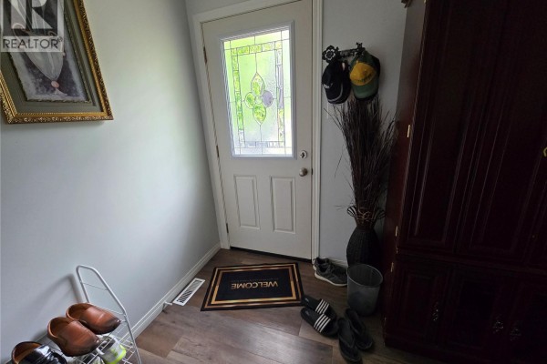 Interior entryway with a white door, shoe rack, and dark wood cabinet. - 152 5th Avenue Se, Swift Current
