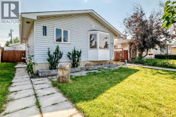 Backyard view with detached garage, snow-covered ground, and red wooden fence - 152 Maranda Close Ne, Calgary