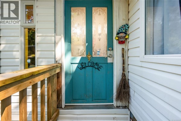 Front exterior of a mobile home with white siding and a wooden deck. - 1520 Mason Trail, Parksville