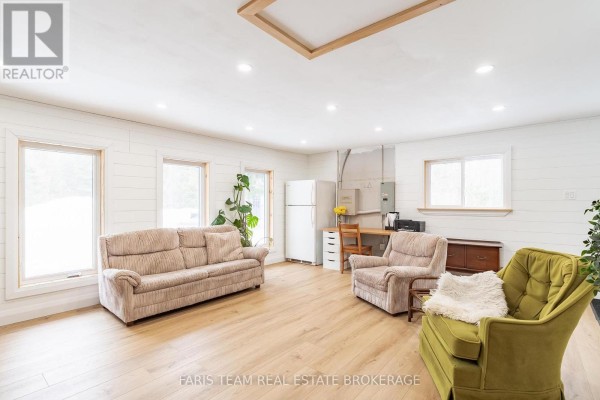 Living room with sofa, armchairs, desk, refrigerator, wood floors, ship lap walls - 1520 Rosemount Road Tay