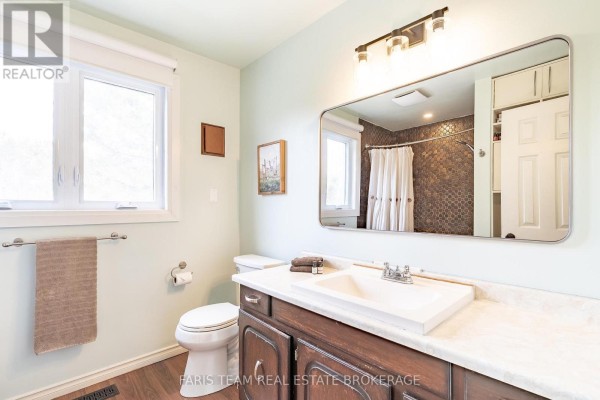 Bathroom with dual sinks, wood vanity, large mirror, and tiled shower - 1520 Rosemount Road Tay