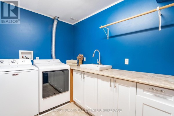 Laundry room with Maytag washer, dryer, sink, and white cabinets - 1520 Rosemount Road Tay