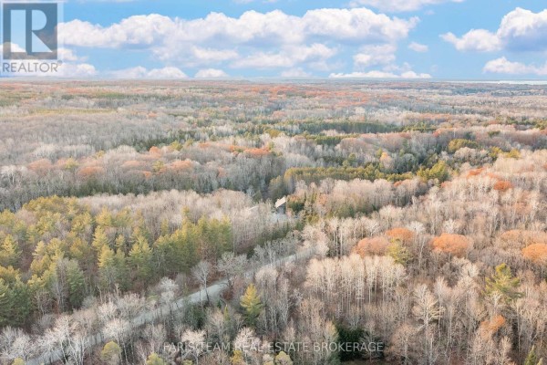 Aerial drone view of a house in a forest with fall colors and a winding road - 1520 Rosemount Road Tay