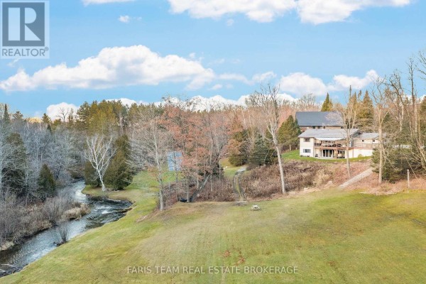 Multi-story house with stream and trees in the yard - 1520 Rosemount Road Tay