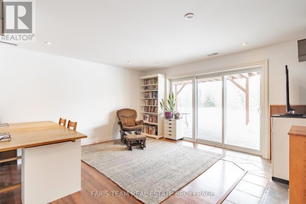 Living room with recliner, bookshelf, and sliding glass door to backyard - 1520 Rosemount Road Tay