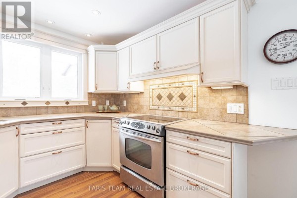 White cabinets, stainless steel stove, tile backsplash & countertops - 1520 Rosemount Road Tay