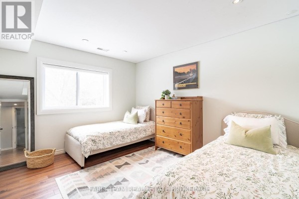 Bedroom with two twin beds, dresser, mirror, and rug - 1520 Rosemount Road Tay