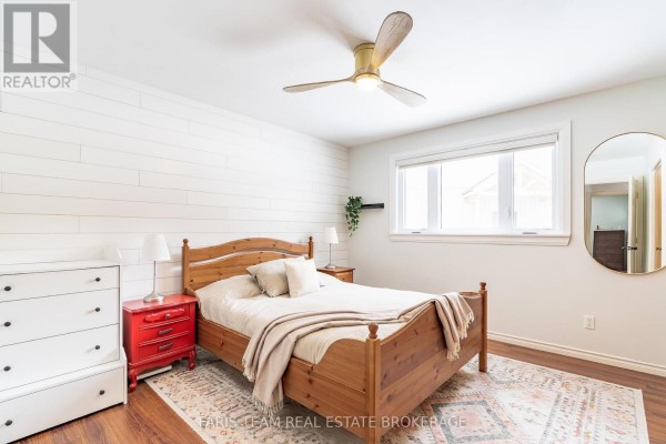 Bedroom with shiplap wall, wood bed, ceiling fan, and oval mirror - 1520 Rosemount Road Tay