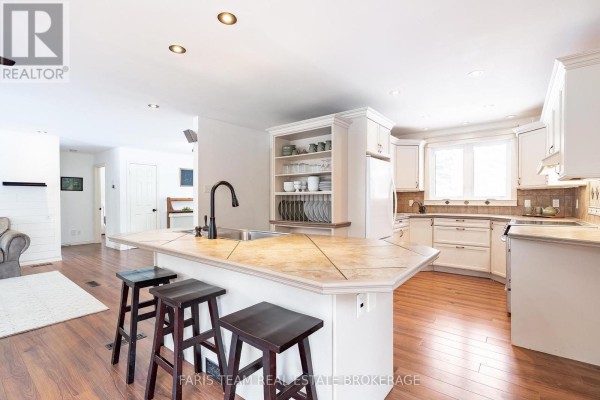 Kitchen with island, white cabinets, and hardwood floors - 1520 Rosemount Road Tay