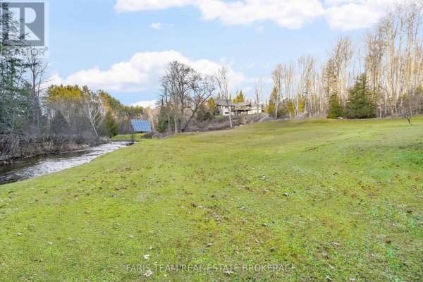 River and grassy field with solar panels and a house on a hill - 1520 Rosemount Road Tay