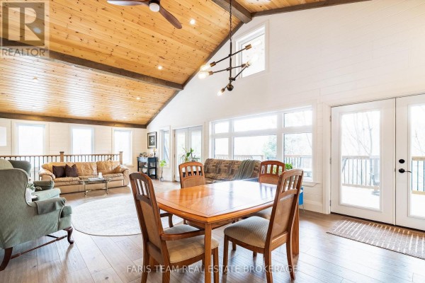 Living room with vaulted wood ceiling, large windows, dining table, sofa, and armchair - 1520 Rosemount Road Tay