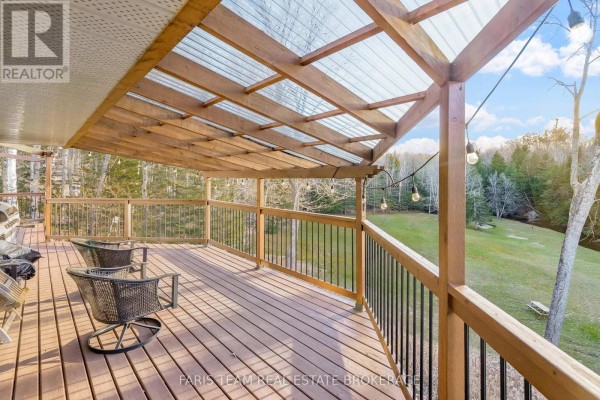 Covered deck with chairs, grill, and string lights overlooking trees - 1520 Rosemount Road Tay