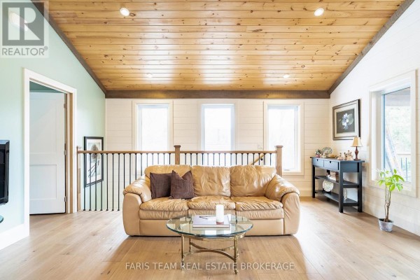 Tan leather sofa and glass coffee table in living room with wood plank ceiling - 1520 Rosemount Road Tay