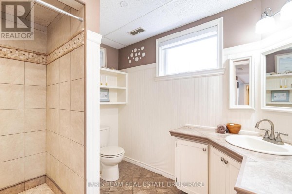 Tiled shower, vanity, sink, toilet, and shelving in bathroom - 1520 Rosemount Road Tay
