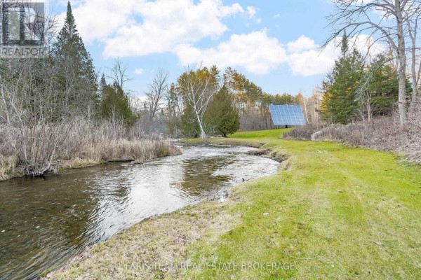 River and solar panels in a green yard with trees - 1520 Rosemount Road Tay