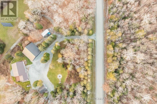 Aerial view of two houses with solar panels and a fire pit on a wooded lot - 1520 Rosemount Road Tay