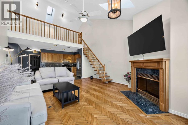 Living room with a fireplace, parquet flooring, a loft, and a kitchen area. - 1520 Venetian Boulevard Unit# M-306, Point Edward