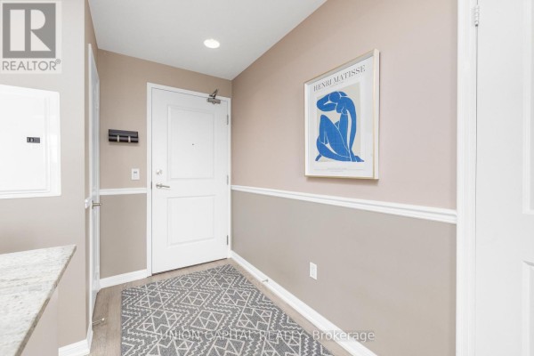Apartment entryway with white door, beige walls, grey patterned rug, and Matisse print. - 1521 - 85 East Liberty Street, Toronto