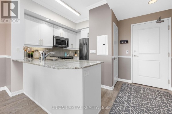 U-shaped kitchen with white cabinets, granite countertops, and stainless steel appliances. - 1521 - 85 East Liberty Street, Toronto