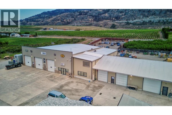 Exterior of a large commercial building with multiple garage doors and an adjacent office section. - 15210 97 Highway, Osoyoos
