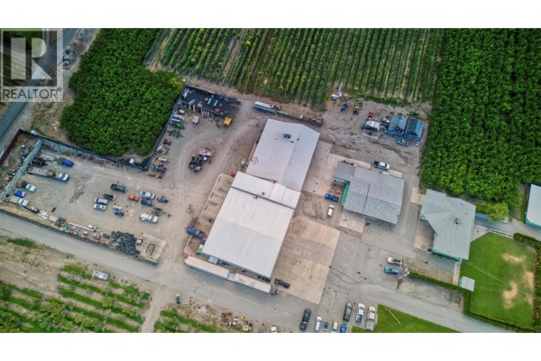 Overhead aerial view of commercial property with large buildings, storage, and agricultural fields. - 15210 97 Highway, Osoyoos
