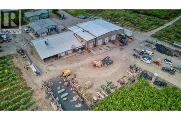 Aerial view of commercial complex with various outbuildings, equipment, and surrounding orchards. - 15210 97 Highway, Osoyoos